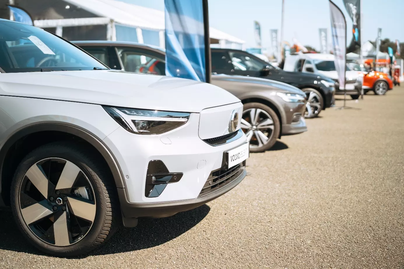 Alignement de voitures neuves exposées en plein air lors d’un salon d'exposants à la Foire du Mans, avec au premier plan un SUV électrique blanc